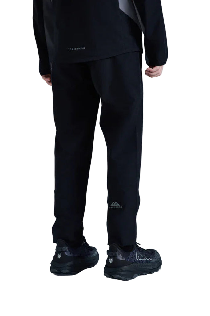 Person wearing black athletic pants with visible brand logos on a light gray background