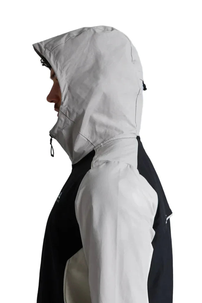 Person wearing a black and white jacket with a hood on a white background