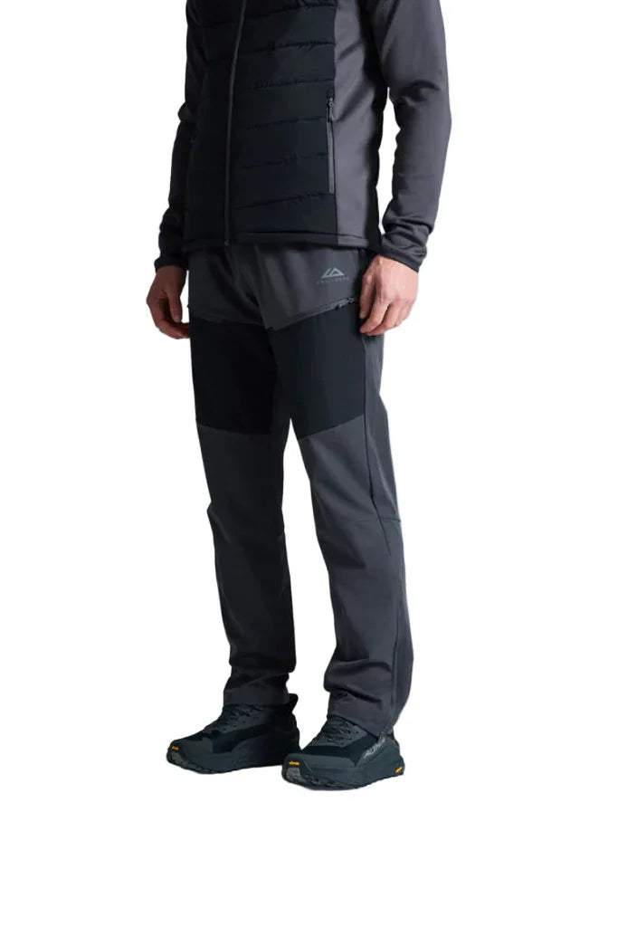 Person wearing a black jacket and pants with a visible brand logo on a light gray background