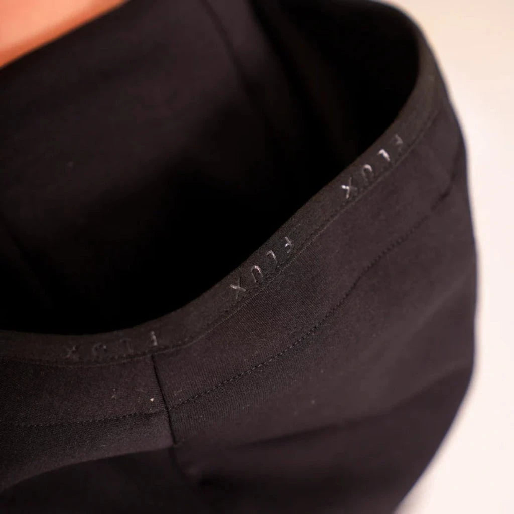 Close-up of a black garment with branding on a neutral background