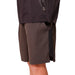 Person wearing dark shorts and a black jacket on a beige background